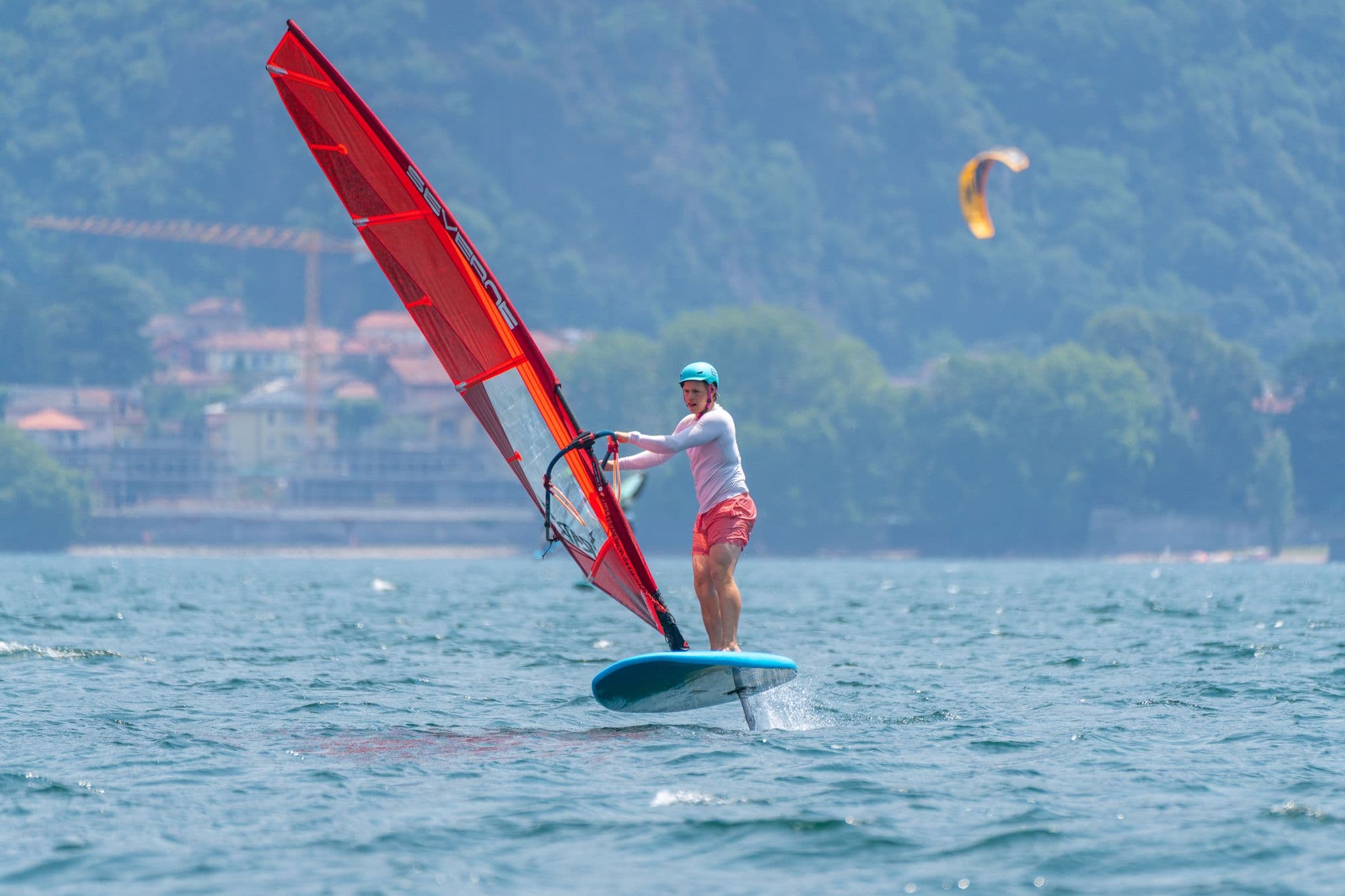 Windsurf-Foiling, ein Kite steht über dem gegenüberliegenden Ufer
