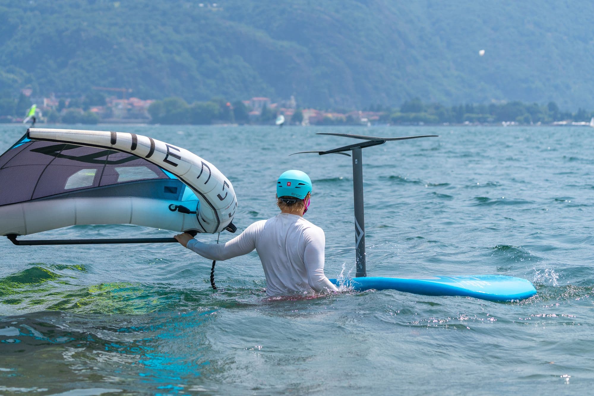 Fahrer im Wasser richtet den Wing auf, Board daneben