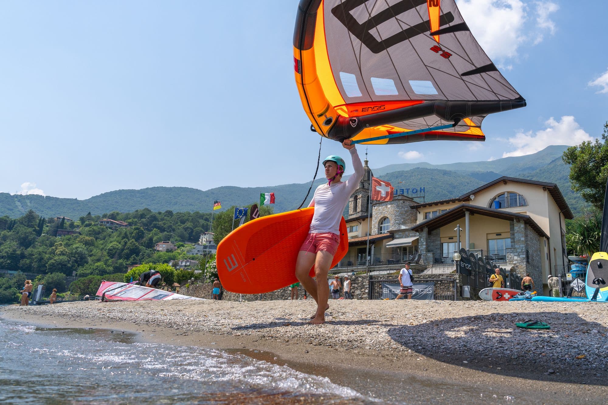 Fahrer trägt Board und Wing aus dem Wasser an den Strand