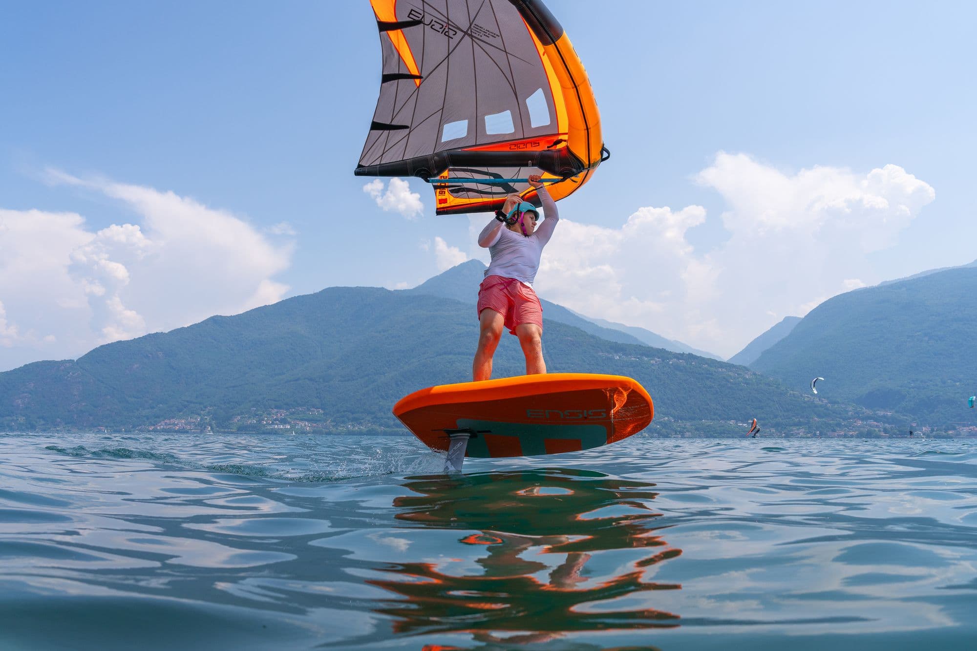 Fahrer mit Wing bei wenig Wind, Berge und Himmel gross im Bild