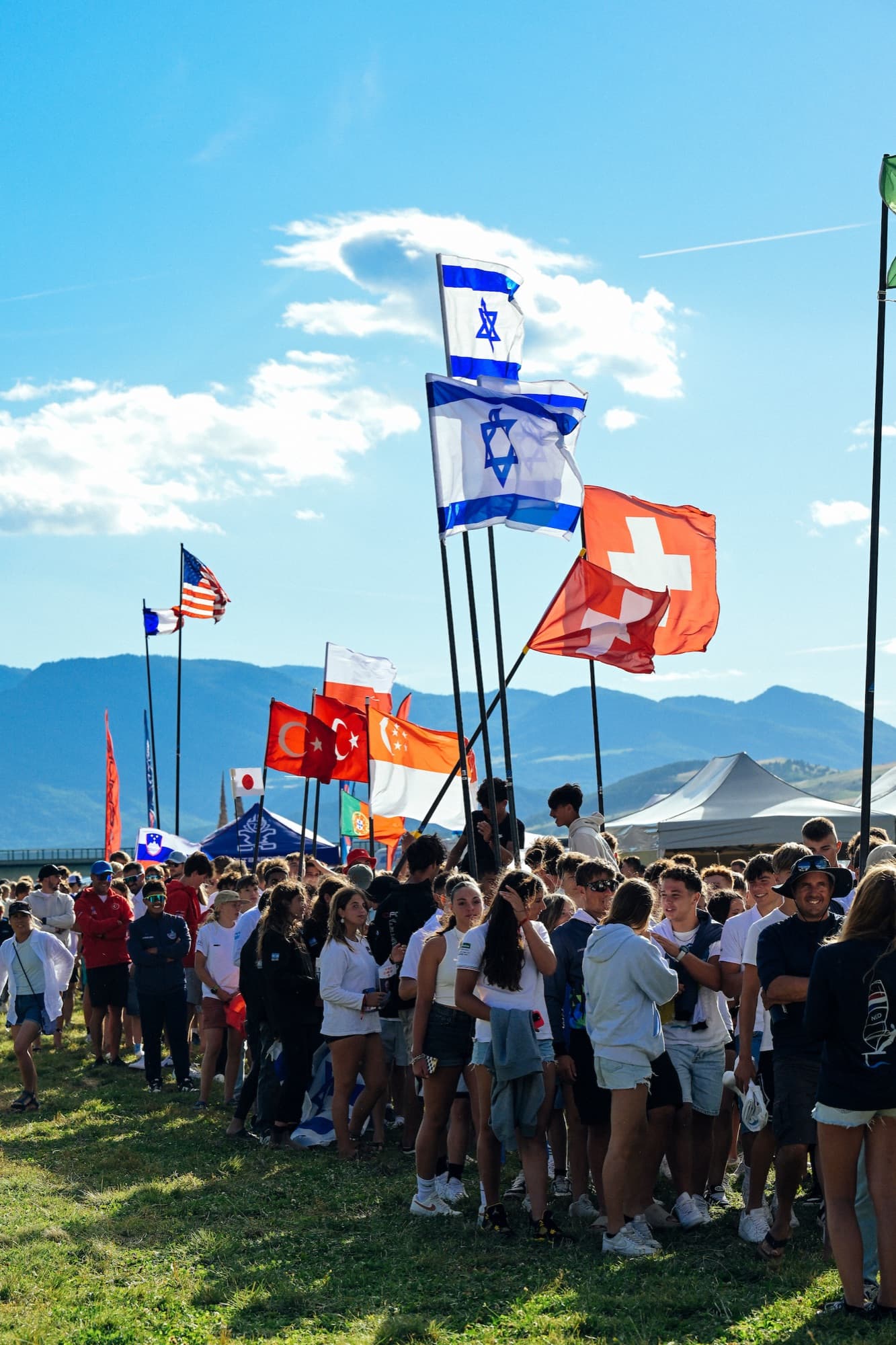 Nationenfahnen über der Menge bei der Eröffnungsfeier, dahinter die Berge der Hautes-Alpes