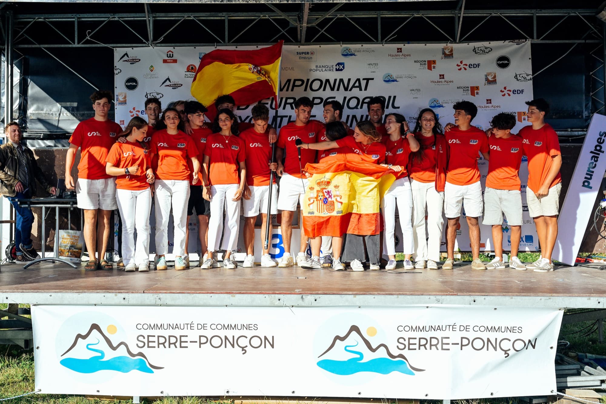 Das spanische Team auf der Bühne vor dem Banner der iQFOiL-Europameisterschaft Youth und Junior