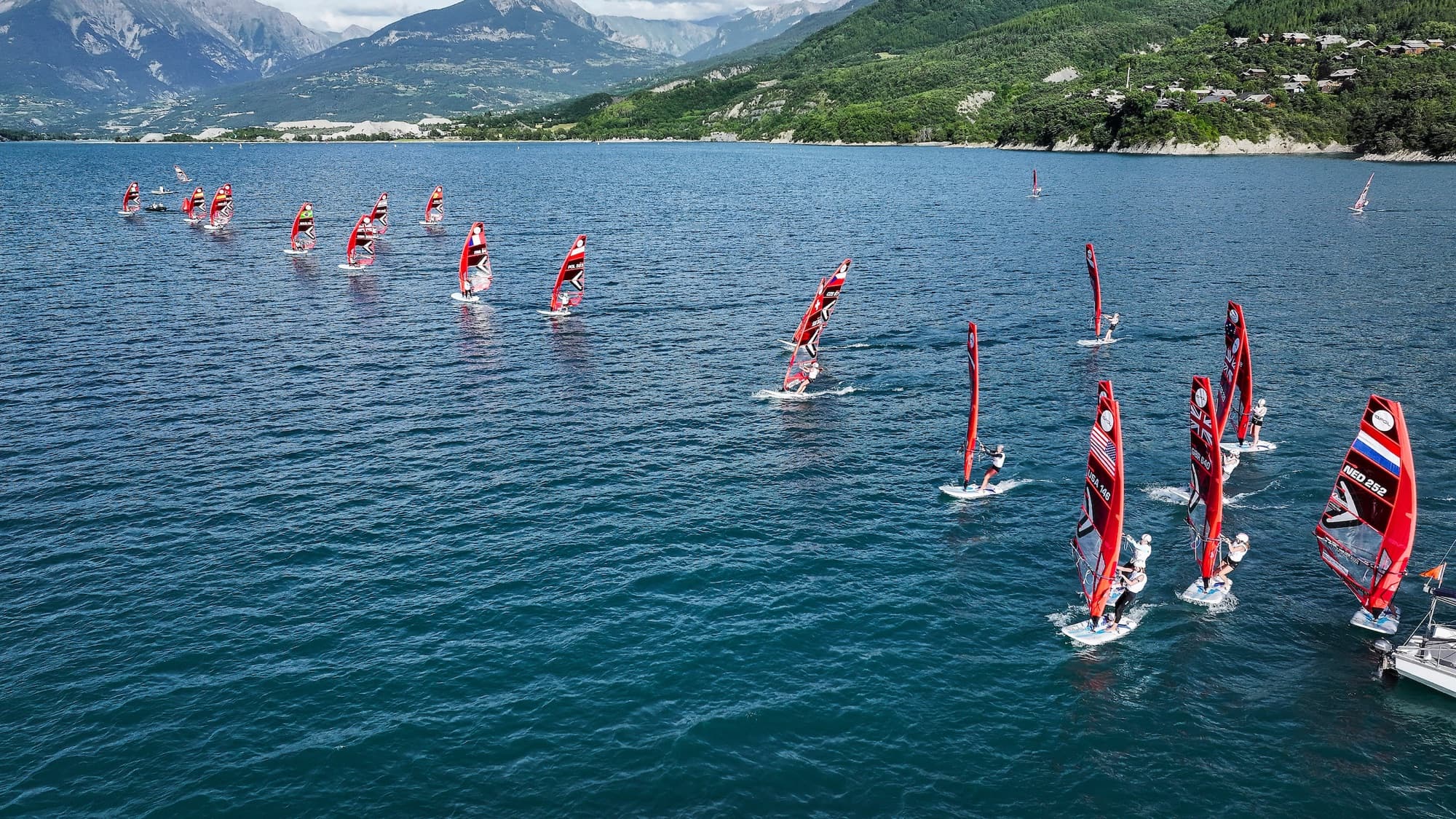 Luftaufnahme bei wenig Wind, die Fahrer verteilen sich über den See, unter anderem USA 148 und NED 252