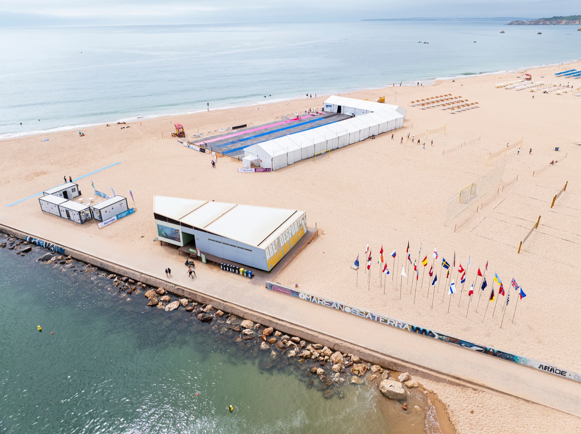 Luftaufnahme des Strandgeländes mit dem Zelt der Regatta, davor die Fahnen der teilnehmenden Nationen