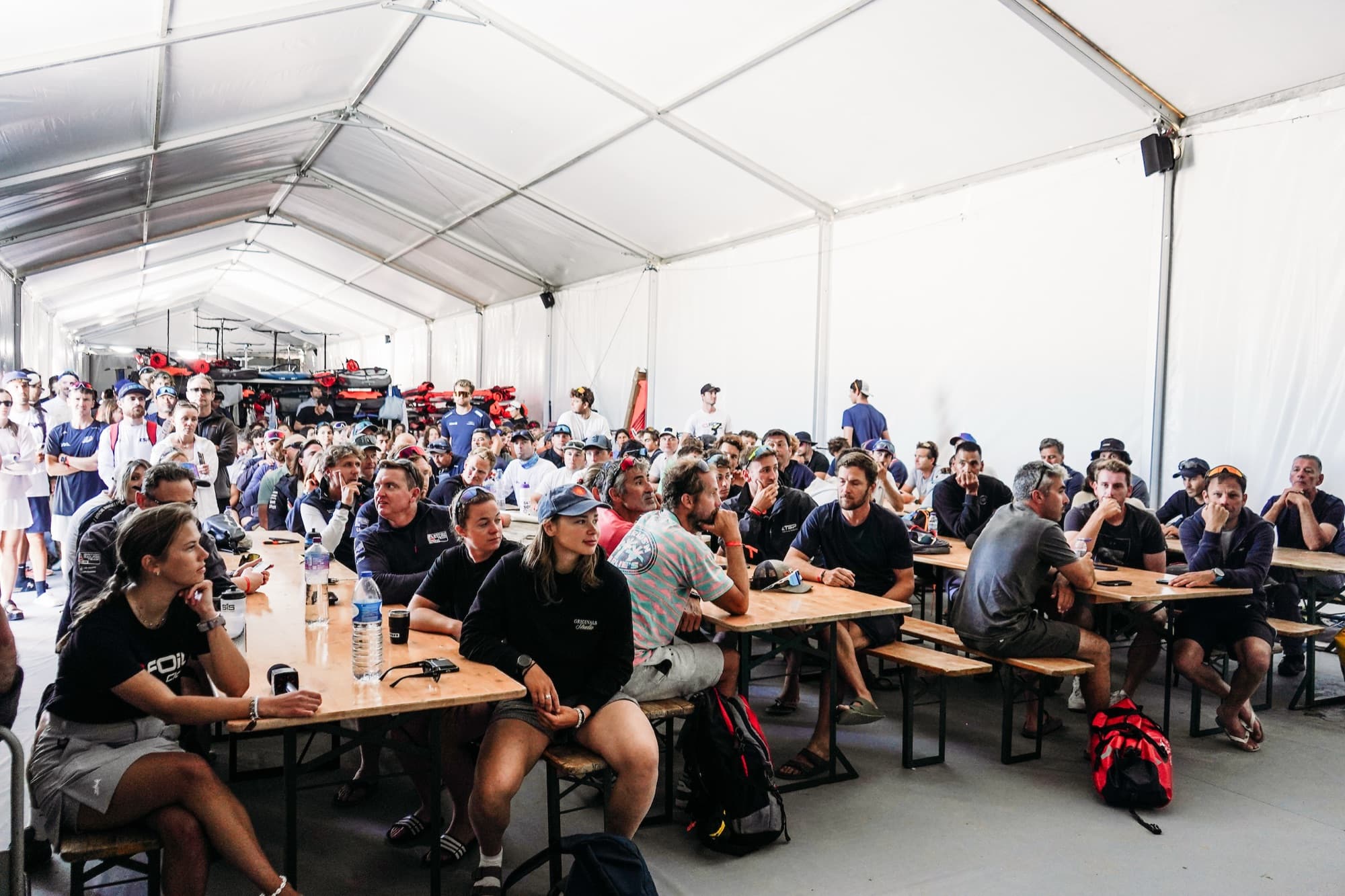 Volles Zelt beim Briefing, die Teilnehmerinnen und Teilnehmer sitzen an langen Holztischen