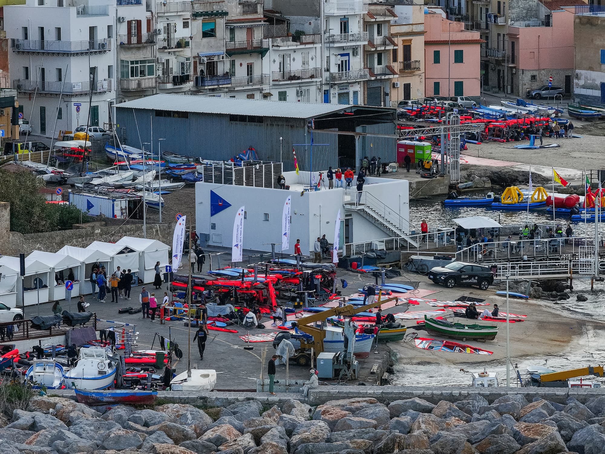 Blick über das Regattagelände am Hafen: Zelte, Materialplatz und Fischerboote zwischen den Häusern