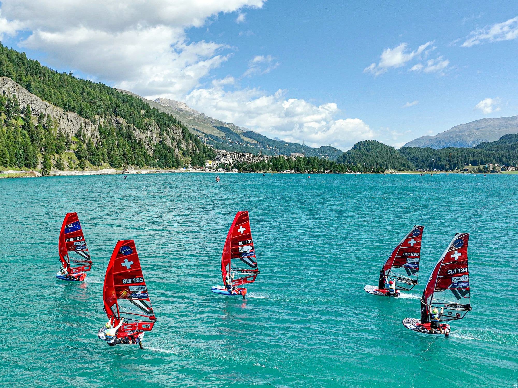 Blick über See und Dorf mit mehreren Fahrern auf dem Wasser