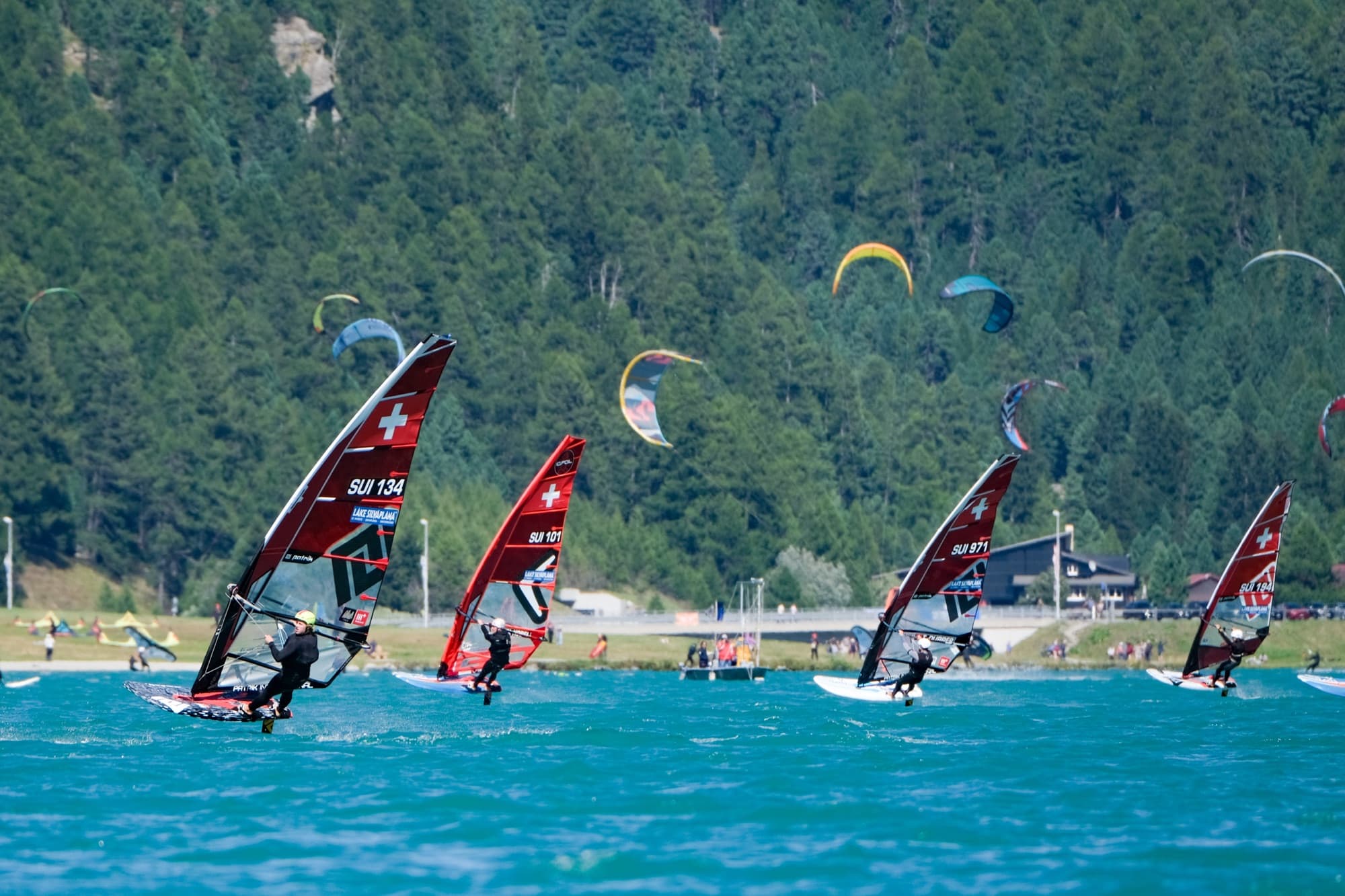 SUI 134 führt eine Viererreihe an, dahinter Kites über dem Ufer