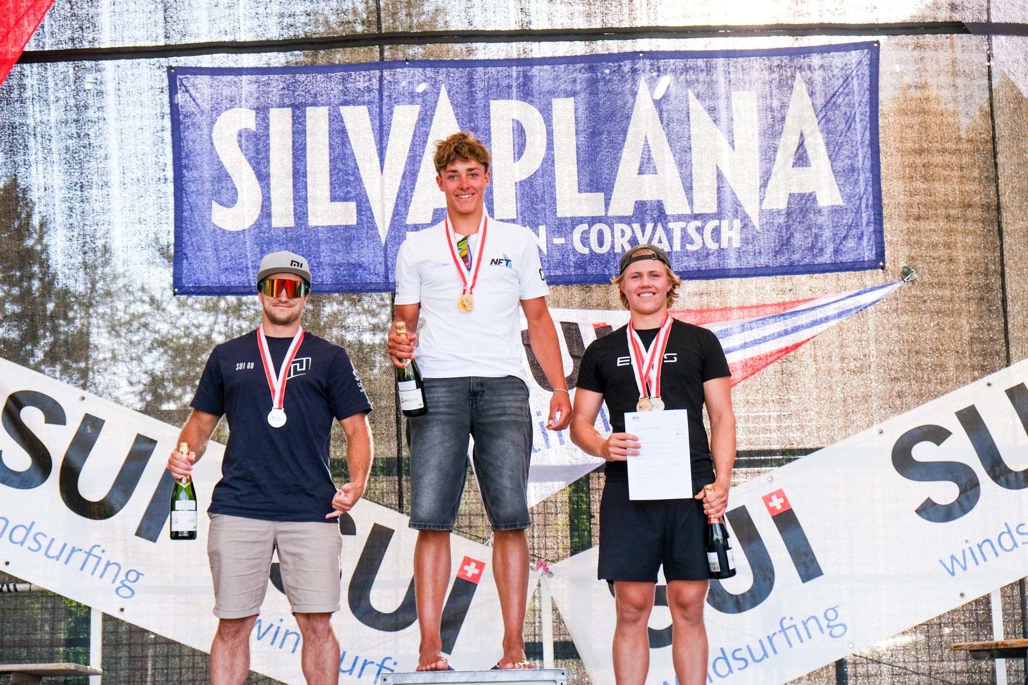 Devin Hauser (rechts, schwarzes Shirt) auf Platz 3 bei einer weiteren Siegerehrung der Schweizermeisterschaft in Silvaplana, mit zwei Medaillen und Urkunde